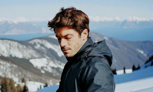 Homme portant une veste urbaine multifonction élégante Vest Paris dans un décor de montagne hivernal représentant la protection technique et le style contemporain