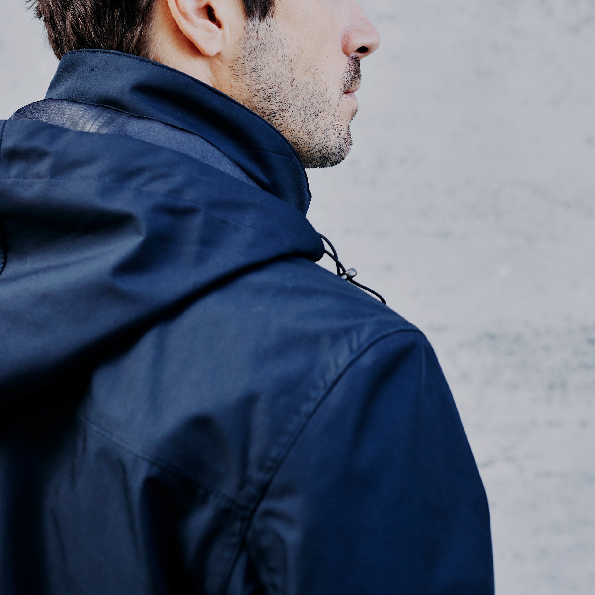 Vue de dos avec capuche de la veste technique longue imperméable